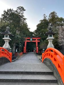 an orange bridge with a red gate and stairs at ゲストハウスHayatamaわびさび in Shingū