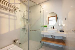 a bathroom with a glass shower and a sink at Grand Lux by BRIO in Danang +63 photos