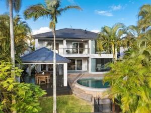 a large house with a swimming pool and palm trees at Capri Garden Stay in Gold Coast