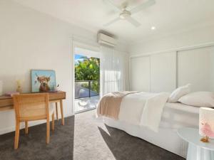a white bedroom with a bed and a desk at Capri Garden Stay in Gold Coast +25 photos
