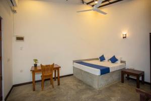 a bedroom with a bed and a table and a chair at Noha Villa in Talpe