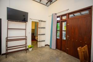 a living room with a tv and a sliding door at Noha Villa in Talpe