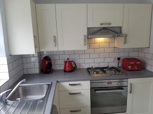 een keuken met witte kasten, een fornuis en een wastafel bij The Annexe in Timsbury