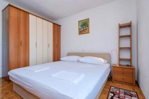 sypialnia z białym łóżkiem i drewnianą szafką w obiekcie MI Apartment w mieście Stari Grad
