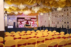 a large room with yellow chairs and chandeliers at Hotel Awadh Grand in Kānpur