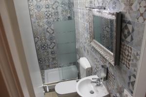 un baño con lavabo y espejo en Victoria House Hostel, en Génova 24 fotos más