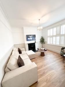 a living room with a white couch and a fireplace at Modern Spacious 4 Bedroom Home in Greater LDN With Garden and Parking in Dartford