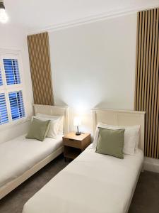 a room with two beds and a table with a lamp at Modern Spacious 4 Bedroom Home in Greater LDN With Garden and Parking in Dartford
