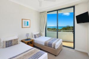two beds in a room with a view of the ocean at Santorini Twin Waters in Mudjimba