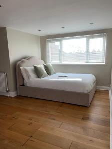 a large bed in a room with a window at Modern Spacious 4 Bedroom Home in Greater LDN With Garden and Parking in Dartford