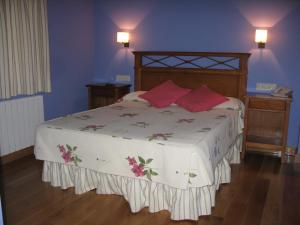 a bedroom with a large bed with red pillows at La Posada de Cucayo in Dobres