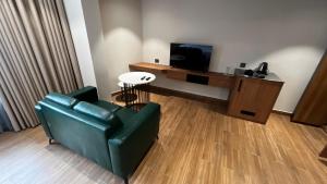 a living room with a green couch and a television at Cloud Nine Hotel in Kottayam +11 photos