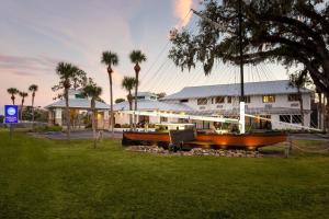 a boat in front of a building with palm trees at PaddleTail Waterfront Lodge, Trademark Collection by Wyndham in Crystal River