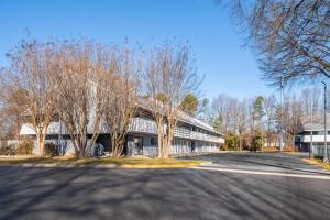 a building with trees in front of a street at Days Inn by Wyndham Charlotte University in Charlotte