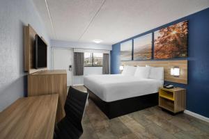 a hotel room with a bed and a desk at Days Inn by Wyndham Charlotte University in Charlotte