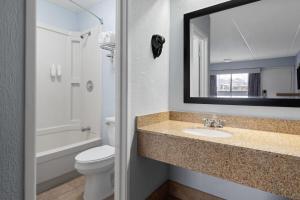 a bathroom with a sink and a toilet and a mirror at Days Inn by Wyndham Charlotte University in Charlotte +31 photos