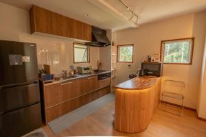 a kitchen with a wooden counter and a black refrigerator at 愛犬と休日を過ごすサウナハウス-COZY HOUSE Izukogen- in Ito +25 photos