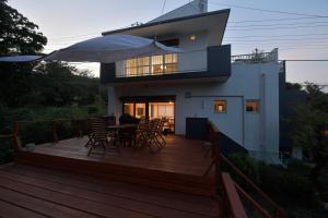 a house with a wooden deck with a table and chairs at 愛犬と休日を過ごすサウナハウス-COZY HOUSE Izukogen- in Ito