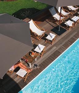 a person sitting in chairs next to a pool with an umbrella at Le Lodge Kerisper in La Trinité-sur-Mer