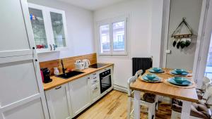 a kitchen with a wooden table and a kitchen with white cabinets at Le Saint-Georges in Berck-sur-Mer