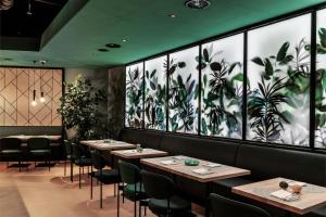 a restaurant with tables and chairs and a wall with plants at Sorell Boutique-Hotel St Peter Zürich in Zurich