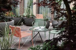 three chairs and a table in a courtyard with plants at Sorell Boutique-Hotel St Peter Zürich in Zurich +40 photos