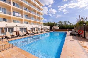 a swimming pool with chairs and a hotel at Invisa Hotel Es Pla - Adults Only in San Antonio