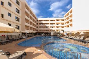 a hotel swimming pool with chairs and a building at Invisa Hotel La Cala in Santa Eularia des Riu