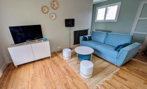 a living room with a blue couch and a tv at Le Saint-Georges in Berck-sur-Mer
