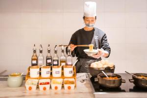 a man in a kitchen preparing food in a kitchen at 成都高新天府三街亚朵酒店 in Chengdu