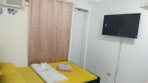 a living room with a yellow couch and a flat screen tv at Jessa's Transient Studio with Balcony in Masbate