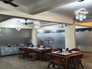 a dining room with tables and chairs and windows at Hotel Fortune Home Residency Near Spectrum Mall Sector 72 in Noida