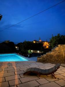 a swimming pool with a chaise lounge next to it at Karst house Žan Pliskovica with private pool in Dutovlje