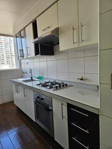 a kitchen with white cabinets and a stove top oven at Apartamentos Santiago Centro R&M in Santiago