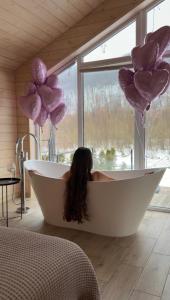 a woman sitting in a bath tub with balloons at Rika chalet in Stantsiya Dembina
