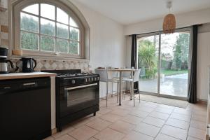 a kitchen with a stove and a table with a view at Villa Au petit baigneur - Maison avec piscine et jardin clos in Challans