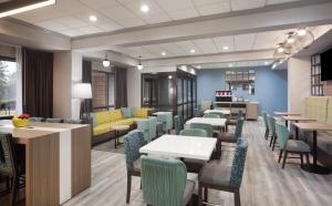 a dining room with tables and chairs and a cafeteria at Hampton Inn - Greenville in Greenville