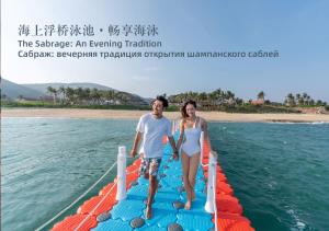 a man and a woman standing on a paddle board in the water at The St. Regis Sanya Yalong Bay Resort in Sanya