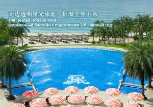 a swimming pool with umbrellas in front of the ocean at The St. Regis Sanya Yalong Bay Resort in Sanya