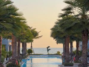 a pool with palm trees and a bird in the distance at The Delfini Hua Hin in Hua Hin +98 photos
