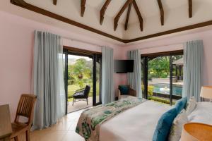 a bedroom with a bed and a view of a pool at Heritage The Villas in Bel Ombre +182 photos