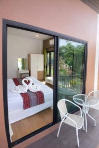 a bedroom with a bed and a balcony with a table at River Bend Villas in Mae Rim