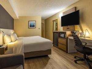 a hotel room with a bed and a desk with a computer at Comfort Inn in Rouyn-Noranda +32 photos