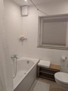 a white bathroom with a tub and a toilet at Ferienwohnung Erlengrund in Mochenwangen