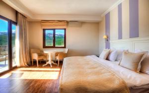 Un dormitorio con una cama grande y una mesa con sillas. en Enastron View Hotel, en Kastoria