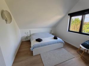 a white bedroom with a bed and a window at Vakantiewoning DRP29 in Zelem