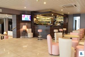 a restaurant with pink chairs and tables and a bar at Hôtel Croix des Bretons - Lourdes Pyrénées in Lourdes