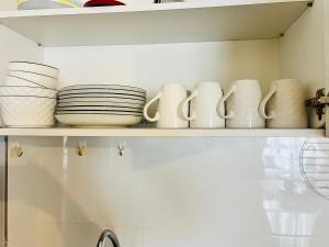 a shelf with plates and bowls on it at JC COZYsTAY RAWANG in Rawang