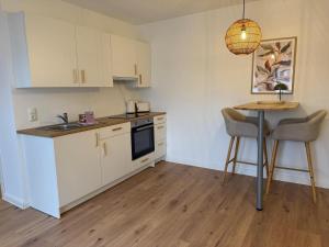 a kitchen with white cabinets and a table with chairs at Nordhavn in Harrislee +6 photos