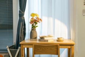 a table with a vase with flowers and a book at LeD Courtyard Homest ay乐东小院民宿 in Beijing
